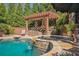 Inviting outdoor space features a stone-trimmed pool, hot tub, waterfall, and covered patio with a stone fireplace at 5473 Heyward Square Pl, Marietta, GA 30068
