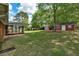 Expansive backyard with lush green lawn, mature trees, screened in porch and storage sheds at 241 Burke Cir, Mcdonough, GA 30253