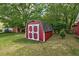 A view of an outbuilding with white trim set on a lawn next to more outbuildings and mature trees at 241 Burke Cir, Mcdonough, GA 30253