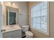 Cozy powder room featuring a single vanity, mirror, and a window for natural light at 4500 Nocohoma Bnd, Douglasville, GA 30135