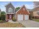 Two-story home showcasing a red brick and gray siding, two-car garage, and landscaped front yard at 1265 Birchwood Ln, Roswell, GA 30076