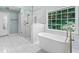 Bright bathroom featuring white marble tile, a glass-enclosed shower, soaking tub, and gold fixtures at 3183 Robinwood Trl, Decatur, GA 30034