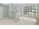 Bright bathroom featuring a soaking tub, glass shower, and white marble tile at 3183 Robinwood Trl, Decatur, GA 30034