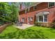 Brick home with a backyard featuring lush green lawn, patio space with outdoor seating, and mature trees at 3380 E Wood Valley Rd, Atlanta, GA 30327