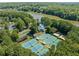 Aerial view of community tennis courts, pool, clubhouse, lake, and surrounding trees at 374 Meadowmeade Cv, Lawrenceville, GA 30043