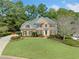 Brick two-story home with manicured lawn, mature trees, and a long driveway in a desirable neighborhood at 374 Meadowmeade Cv, Lawrenceville, GA 30043