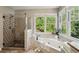 Spacious bathroom with a glass shower, garden tub, and large window at 550 Ambergate Ct, Roswell, GA 30076