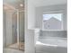 Modern bathroom showcasing a tiled walk-in shower, soaking tub, and a window for natural lighting at 115 Felicity Pike, Locust Grove, GA 30248