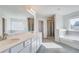Bright bathroom with double sink vanity, large mirror, separate shower, and tub with tiled surround at 115 Felicity Pike, Locust Grove, GA 30248