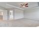 Large bedroom featuring tray ceiling, ceiling fan, plush carpeting, and adjacent bathroom entry at 115 Felicity Pike, Locust Grove, GA 30248