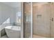 Bathroom featuring a freestanding tub, glass-enclosed shower with tile surround, and a sunny window at 123 Felicity Pike, Locust Grove, GA 30248