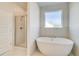 Bright bathroom features a glass enclosed shower and soaking tub by a window at 123 Felicity Pike, Locust Grove, GA 30248