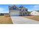 Stunning two-story home with brick accents, gray siding, a pristine lawn, and an expansive driveway at 123 Felicity Pike, Locust Grove, GA 30248