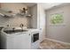 Functional laundry room with modern washer and dryer units, a window for natural light, and convenient storage shelves at 19 Four Feathers Ne Ln, Rydal, GA 30171
