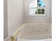 Close-up of jacuzzi-style bathtub with gold hardware and natural light from a window above at 1704 Golf Link Dr, Stone Mountain, GA 30088