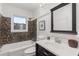 Well-lit bathroom featuring dark-toned vanity, square mirror, and tub and shower with mosaic tile at 404 Bridlewood Cir, Decatur, GA 30030