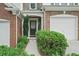 Home's inviting entryway features a dark front door, lush green bushes and brick accents at 1491 Bellsmith Dr, Alpharetta, GA 30076