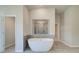 Soaking tub in a bright bathroom with tile flooring, large tub, and neutral color palette at 174 Haverling Pass, Hampton, GA 30252