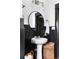 Stylish bathroom with black wainscoting, pedestal sink, round mirror, and modern vanity lighting at 836 Dill Sw Ave, Atlanta, GA 30310