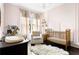 Comfortable Bedroom with a white armchair, a golden metal crib, and soft colors creating a tranquil atmosphere at 836 Dill Sw Ave, Atlanta, GA 30310