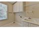 Functional laundry room with storage cabinets, sink, and tile flooring at 870 Longstone Lndg, Alpharetta, GA 30022