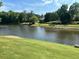Scenic view of a serene pond surrounded by lush greenery, complemented by a manicured lawn at 870 Longstone Lndg, Alpharetta, GA 30022