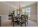 Traditional dining room with wood table, chandelier, wainscoting, and large window overlooking outside at 1060 Crescent Ridge Dr, Buford, GA 30518