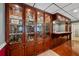 Basement bar area features custom wood cabinetry, glass display cases and hardwood flooring at 215 The Farm Rd, Mcdonough, GA 30252