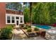 Exterior view of house with pool, brick wall, green bushes, and tall trees in the background at 215 The Farm Rd, Mcdonough, GA 30252