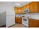 Compact kitchen with white appliances, light wood cabinets, and tile flooring at 215 The Farm Rd, Mcdonough, GA 30252