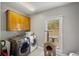 Practical laundry room with modern washer and dryer, storage cabinets, and a window for natural light at 215 The Farm Rd, Mcdonough, GA 30252