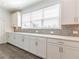 Bright kitchen offers sleek white cabinets, stylish hardware, light countertops and backsplash, plus a large window at 3409 Catalan Aly, Decatur, GA 30032