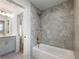 This bathroom features gray wall tiles, a tub, and an adjacent vanity with modern fixtures at 4201 Hosch Reserve Dr, Buford, GA 30519