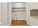 Open laundry room featuring hardwood floors, wood shelving, and connections for washer and dryer at 705 Trickum Valley Dr, Woodstock, GA 30188