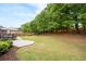 Expansive backyard features a patio with dining set, leading to a well-maintained lawn and a backdrop of mature trees at 1031 Ludwick Way, Lawrenceville, GA 30046