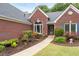 Close-up of a brick home's entrance with colorful flower beds, a walkway, and manicured shrubs at 1031 Ludwick Way, Lawrenceville, GA 30046