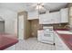 Kitchen featuring white cabinets, white appliances and maroon countertops at 1220 Paddocks Way, Powder Springs, GA 30127