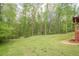 This large backyard features a green lawn, trees, and partial shade at 128 Partridge Rdg, Woodstock, GA 30188