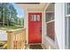 A charming red front door with a new welcome mat and a vibrant flower garden offers curb appeal at 128 Partridge Rdg, Woodstock, GA 30188