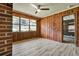 Bright sunroom with wood paneling, a brick accent, laminate floors, and an open doorway at 3137 Ardley Sw Rd, Atlanta, GA 30311