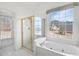 Sunlit bathroom with a shower, tub, and windows that boast treed views of the surrounding area at 1268 Windsor Glen Dr, Douglasville, GA 30134