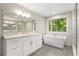 Bathroom featuring a soaking tub, walk-in shower, and double vanity with a bright window view at 660 Willow Knoll Se Dr, Marietta, GA 30067
