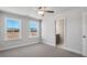 Carpeted bedroom with ceiling fan, two windows, and an open door leading to the bathroom at 124 Aj Welch Jr Way, Mcdonough, GA 30252