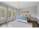 This bedroom boasts large windows, a charming chandelier, and a soft patterned rug over hardwood floors at 126 Abbington River Ln, Atlanta, GA 30339