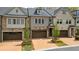 Attractive townhome featuring a two-car garage, lush landscaping, and tasteful stone details at 126 Abbington River Ln, Atlanta, GA 30339