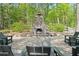Close-up of a stone outdoor fireplace with a seating area in wooded area at 126 Abbington River Ln, Atlanta, GA 30339