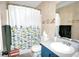 A full bathroom with ceramic tiling, toilet, tub and shower with decorative curtain and blue vanity sink at 2176 Cold Springs Cir, Lithonia, GA 30058