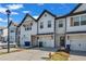 A row of townhomes featuring white siding, garages, black trim and timber accents creating a cohesive community aesthetic at 4142 Spring Valley Cir # 65, Tucker, GA 30084