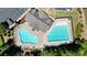 An aerial view highlights two sparkling pools, with one being kidney-shaped, next to a parking lot and picnic area at 526 Lost Creek Dr, Woodstock, GA 30188