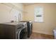 Laundry room featuring a modern washer and dryer set, tile flooring, and a bright window at 526 Lost Creek Dr, Woodstock, GA 30188